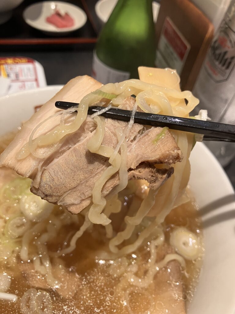 Photo of Kitakata ramen noodles and char siu being picked up with chopsticks