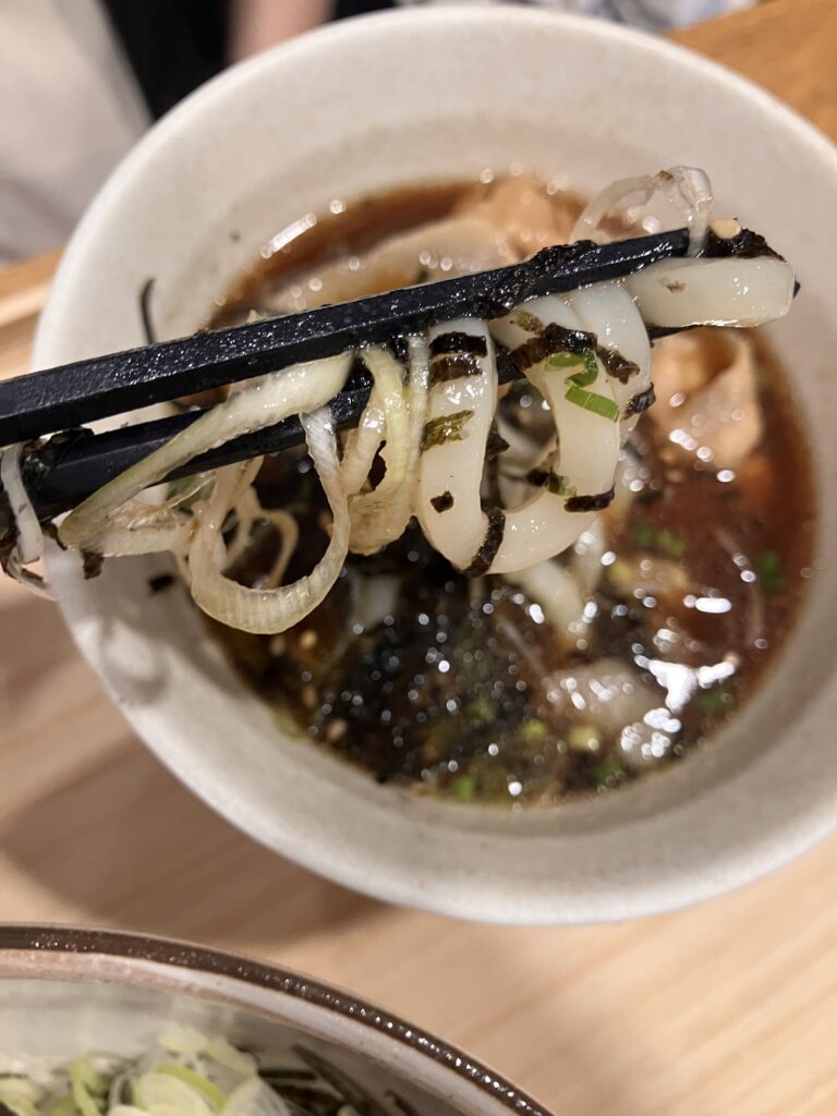 Photo of pork udon noodles being picked up with chopsticks