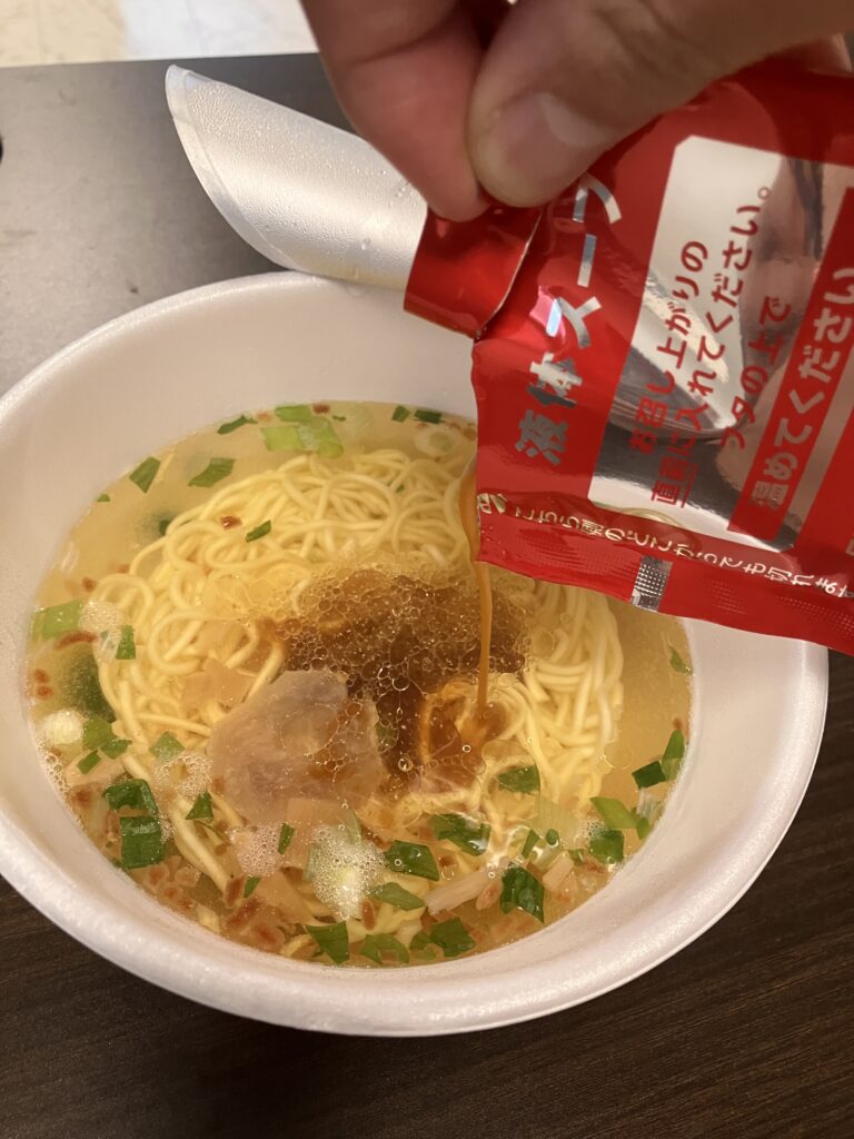 A photo of liquid soup being poured into a cup noodle