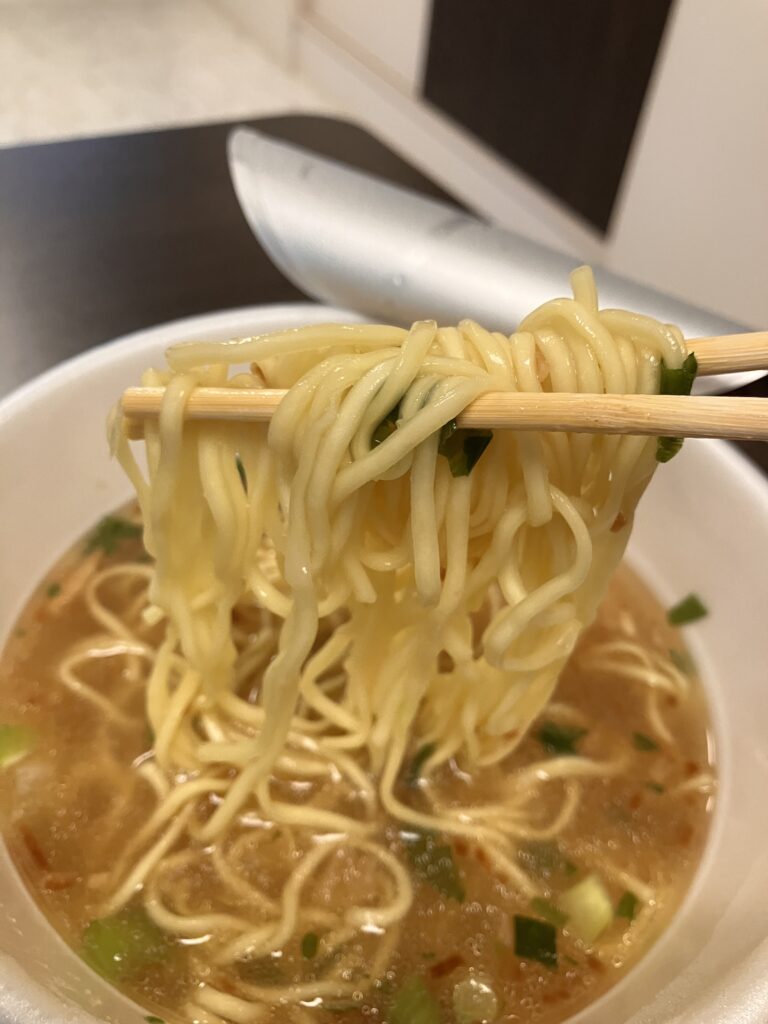 A photo of the noodles in a cup noodle being held up by the edge