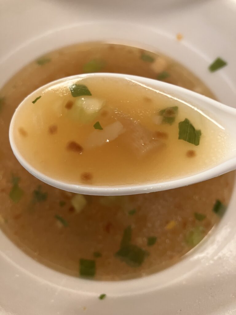 A photo of the soup in a cup noodle being held up by a spoon