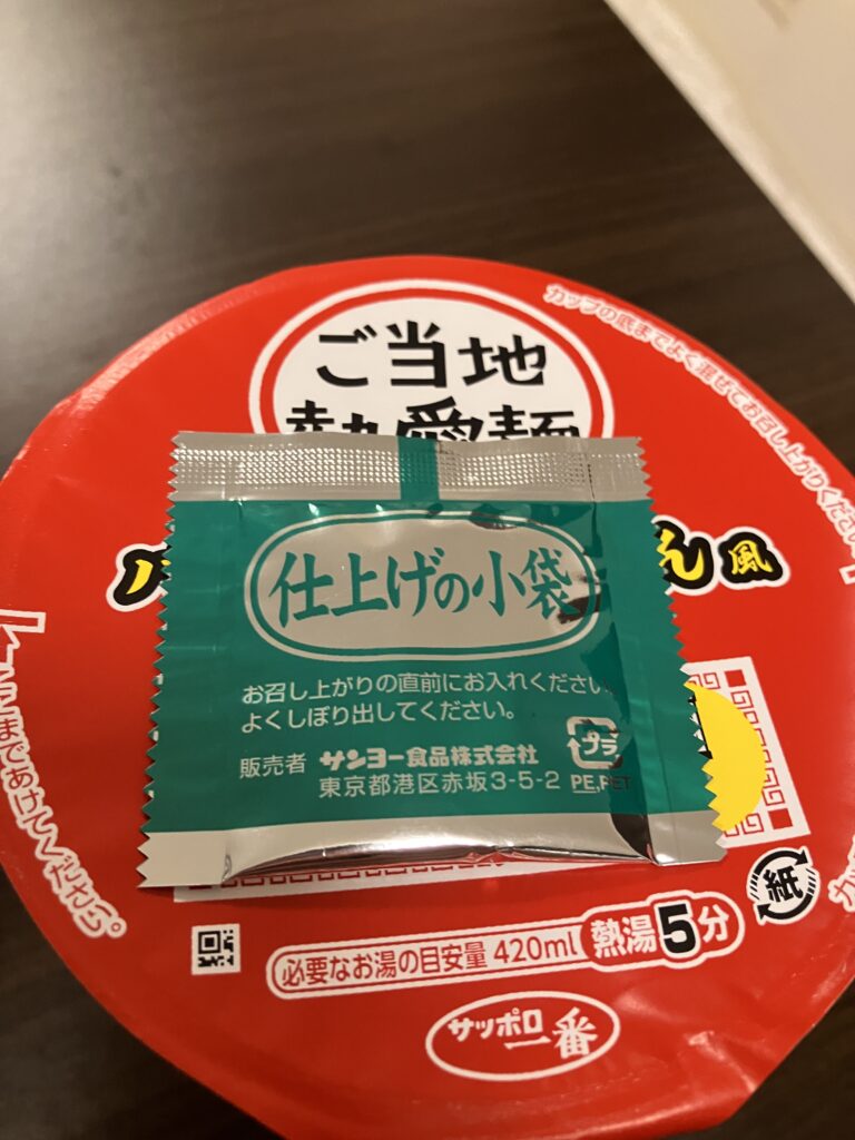 A photo of sauce being placed on the lid of a cup noodle and heated