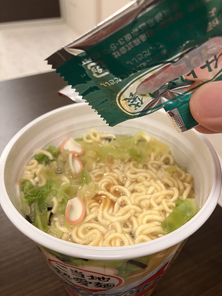 A photo of the finishing sauce being added to the cup noodle