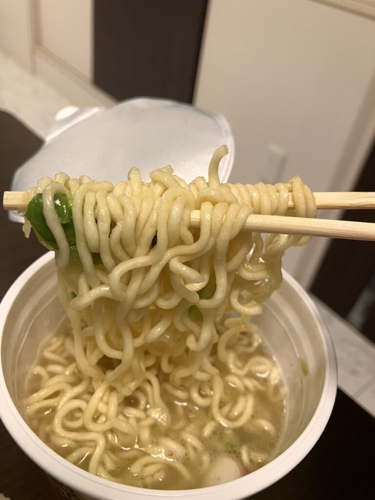 A photo of the noodles being picked up with chopsticks