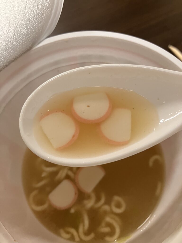A photo of the soup from a cup noodle being scooped up with a spoon