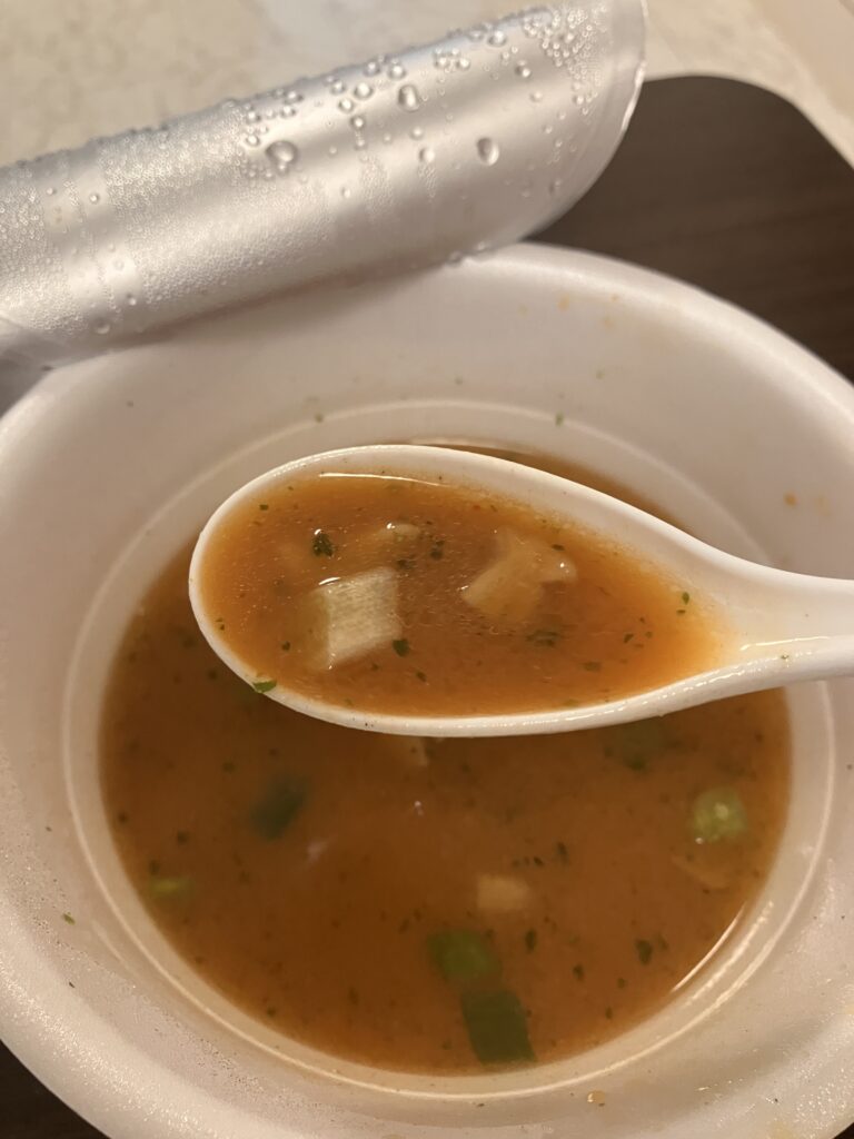 A photo of the cup ramen soup being picked up with a spoon