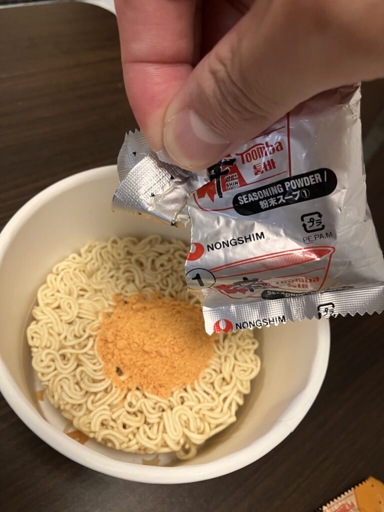 Pouring powdered soup into cup ramen