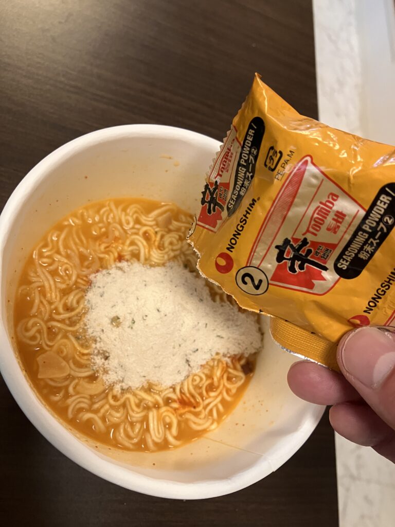 Pouring a second batch of powdered soup into cup ramen